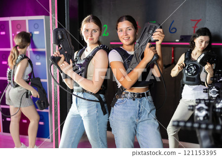Two cheerful and happy girls friends pose in locker room before laser tag match. 121153395