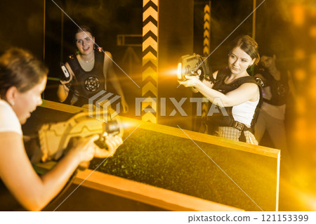 Portrait of excited girlfriends playing enthusiastically laser tag game two teams opposite each other in room Portrait of excited girlfriends playing enthusiastically laser tag game two teams opposite each other in room 121153399