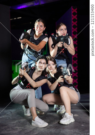 Four happy girls with laser pistols in their hands in dark laser tag room Four happy girls with laser pistols in their hands in dark laser tag room 121153400