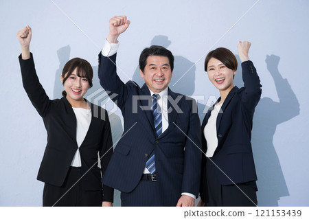 商務套裝中的多項成功，看著鏡頭，畫面上有拳頭揮舞、努力嘗試、淺藍色背景的影像 121153439