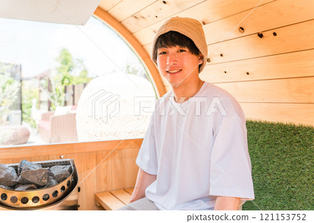 Young Asian man wearing a sauna hat in a sauna Young Asian man wearing a sauna hat in a sauna 121153752
