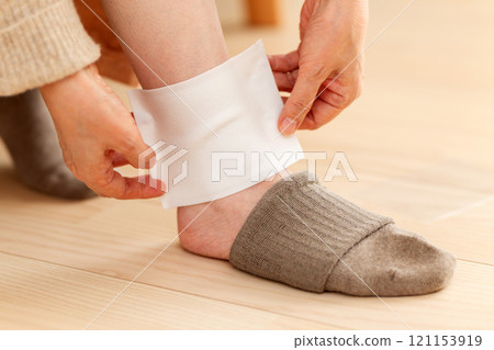 Middle-aged to senior women applying a compress to their ankles 121153919