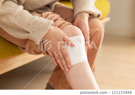 Middle-aged to senior women applying a compress to their knees 121153948