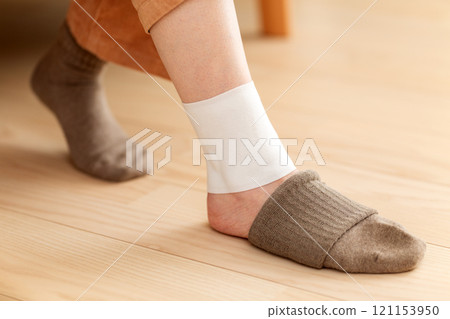 Middle-aged to senior women applying a compress to their ankles 121153950