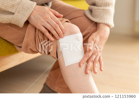 Middle-aged to senior women applying a compress to their knees Middle-aged to senior women applying a compress to their knees 121153960