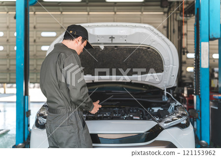 Male auto mechanic checking car engine room using tablet Male auto mechanic checking car engine room using tablet 121153962