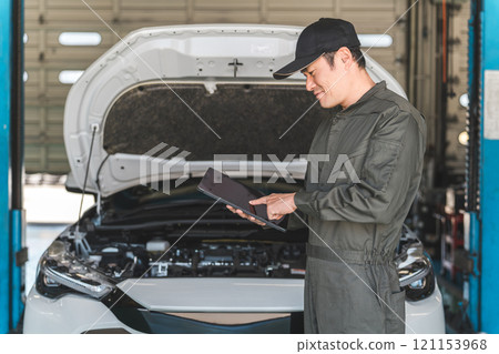 男性汽車機械師使用平板電腦檢查汽車的引擎室 男性汽車機械師使用平板電腦檢查汽車的引擎室 121153968