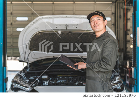 Male auto mechanic checking car engine room using tablet Male auto mechanic checking car engine room using tablet 121153970
