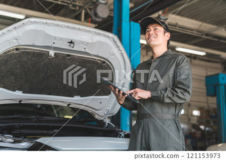 男性汽車機械師使用平板電腦檢查汽車的引擎室 121153973