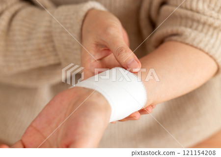 A middle-aged to senior woman holding her bandaged wrist 121154208