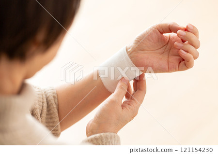 A middle-aged to senior woman holding her bandaged wrist A middle-aged to senior woman holding her bandaged wrist 121154230