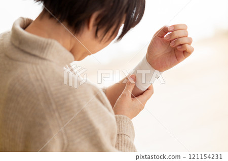 握著纏著繃帶的手腕的中高級婦女 握著纏著繃帶的手腕的中高級婦女 121154231