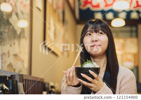 A woman eating a seafood bowl with gusto. Photo courtesy of Peer Bandai. 121154900