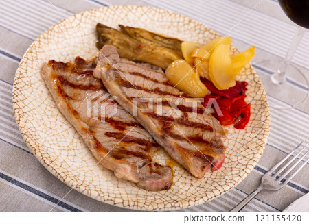 On plate two pieces of barbecue beef with fried vegetables - eggplant slices and green bell peppers On plate two pieces of barbecue beef with fried vegetables - eggplant slices and green bell peppers 121155420