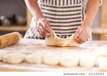 Closeup on pastry chef woman's hands rolling out dough with rolling pin at bakery, culinary arts Closeup on pastry chef woman's hands rolling out dough with rolling pin at bakery, culinary arts 121155451