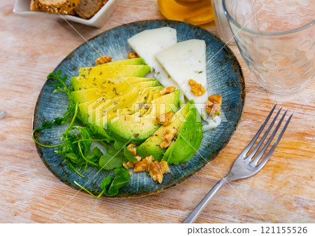 Avocado and cheese served with arugula and walnuts Avocado and cheese served with arugula and walnuts 121155526