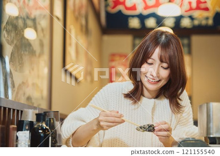 A woman eating oysters with relish. Photo courtesy of Pier Bandai. 121155540