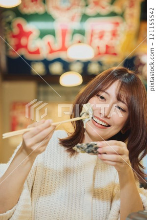 A woman eating oysters with relish. Photo courtesy of Pier Bandai. 121155542