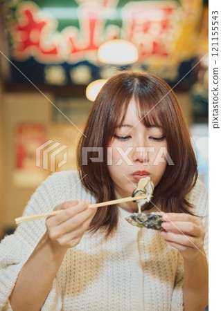 A woman eating oysters with relish. Photo courtesy of Pier Bandai. 121155543