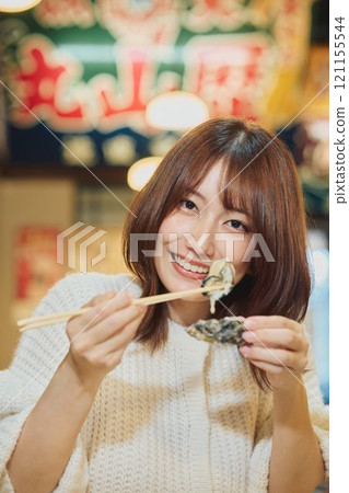 A woman eating oysters with relish. Photo courtesy of Pier Bandai. 121155544