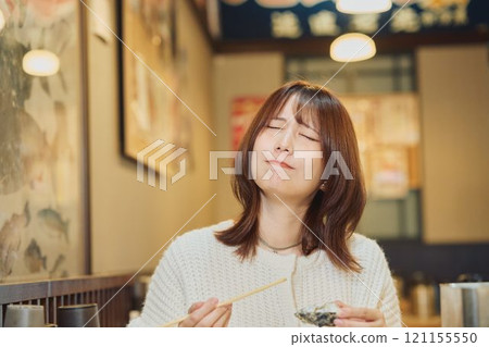 一位女士正在美味地吃牡蠣 攝影由 Pia Bandai 提供。 一位女士正在美味地吃牡蠣 攝影由 Pia Bandai 提供。 121155550