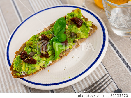 Sandwich with cheese and guacamole, dried tomatoes and seeds 121155570