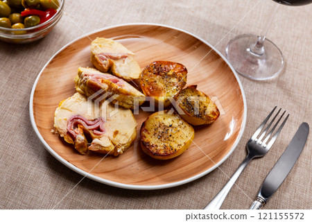 Stuffed chicken served with potatoes on platter 121155572