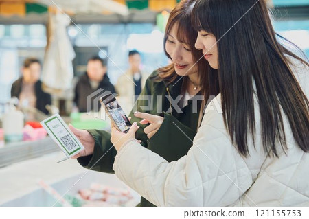 Women making QR code payments at a fish market. Photo courtesy of Peer Bandai. 121155753