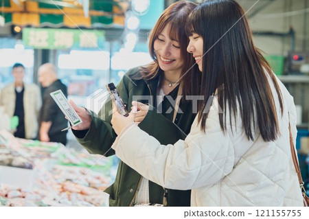 Women making QR code payments at a fish market. Photo courtesy of Peer Bandai. 121155755