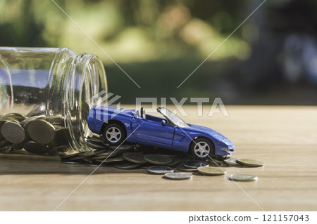 Coins with glass bottle and blue car, business saving and investment concept. Coins with glass bottle and blue car, business saving and investment concept. 121157043
