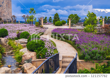 a fabulously beautiful blooming garden with a stream, paths, bushes and flower beds. a fabulously beautiful blooming garden with a stream, paths, bushes and flower beds. 121157782