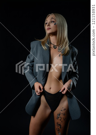 Elegantly styled model poses confidently in a dark setting during a photo shoot Elegantly styled model poses confidently in a dark setting during a photo shoot 121158931