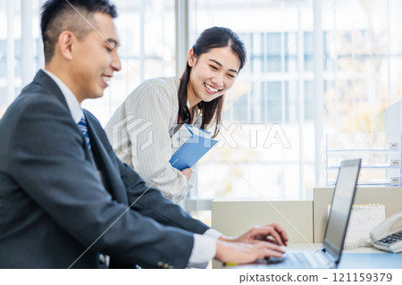 Business person talking with colleague in office 121159379