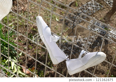 Indoor shoes hanging out to dry on a clothes hanger 121162875