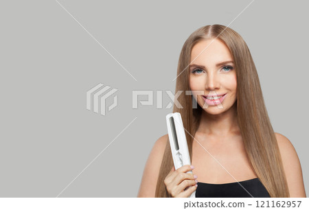 Glad brunette lady with straight hair holding straightening iron on white background.  121162957