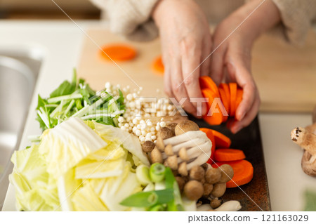 Hands of a middle-aged to senior woman cutting vegetables for a hot pot dish in the kitchen Hands of a middle-aged to senior woman cutting vegetables for a hot pot dish in the kitchen 121163029