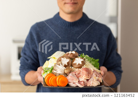 中年男子拿著雞湯鍋的配料 中年男子拿著雞湯鍋的配料 121163452