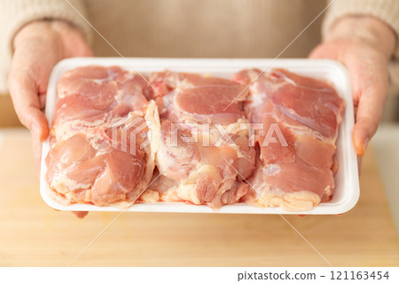Hands of a middle-aged to senior woman holding chicken in the kitchen Hands of a middle-aged to senior woman holding chicken in the kitchen 121163454