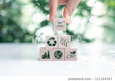 Hand put wooden cubes with green net zero icon and green icon on bokeh nature. Net zero and carbon neutral concept. Net zero greenhouse gas emissions target. Climate neutral long term strategy. 121164567