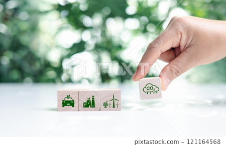Hand put wooden cubes with green net zero icon and green icon on bokeh nature. Net zero and carbon neutral concept. Net zero greenhouse gas emissions target. Climate neutral long term strategy. 121164568