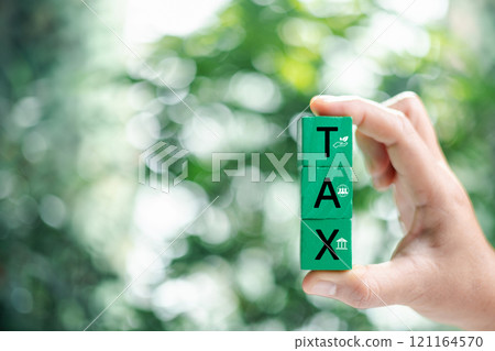 Hand holding word TAX on wooden cube. ESG Concepts in Environment, Society and Governance Invest. limit global warming from A climate-neutral long-term strategy greenhouse gas emissions targets. 121164570