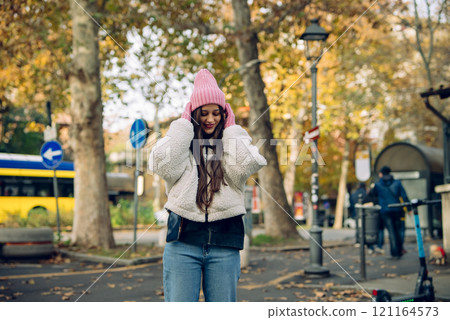 Stylish Young Woman Indulging in the Beauty of Autumn While Enjoying a City Park 121164573