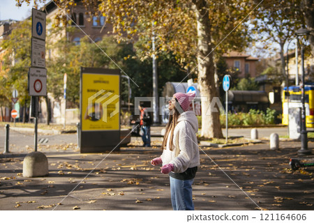 A Young Woman Enjoying an Autumn Day in a Park Surrounded by Trees and an Urban Backdrop A Young Woman Enjoying an Autumn Day in a Park Surrounded by Trees and an Urban Backdrop 121164606