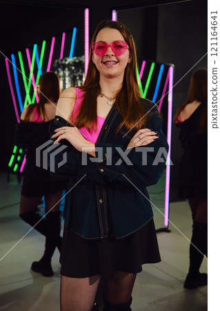 Confident young woman posing with neon lights in a modern studio setting during evening hours Confident young woman posing with neon lights in a modern studio setting during evening hours 121164641