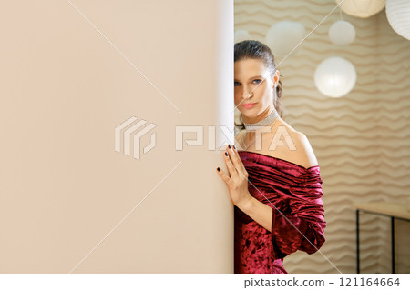 Fashionable woman poses elegantly beside a wall in a stylish indoor setting Fashionable woman poses elegantly beside a wall in a stylish indoor setting 121164664