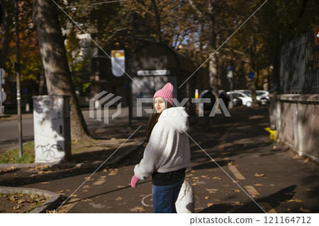 A Woman Enjoying a Leisurely Stroll in an Autumn Park While Dressed in a Cozy Outfit A Woman Enjoying a Leisurely Stroll in an Autumn Park While Dressed in a Cozy Outfit 121164712