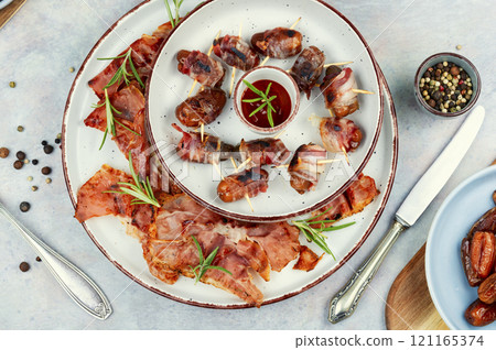 Elegant appetizer featuring bacon-wrapped dates. Elegant appetizer featuring bacon-wrapped dates. 121165374