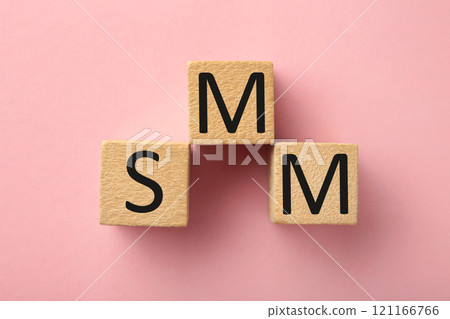 Wooden cubes with word SMM on pink background. Wooden cubes with word SMM on pink background. 121166766