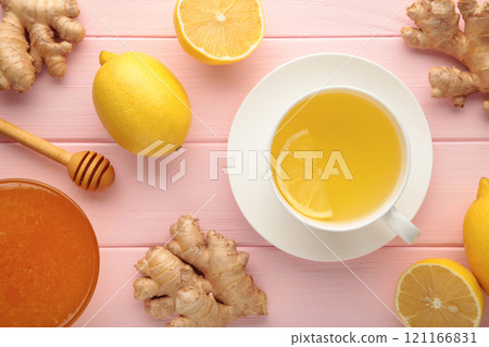 Ginger tea with lemon in a white cup on pink wooden background. 121166831