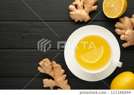 Ginger tea with lemon in a white cup on blakc wooden background. 121166844